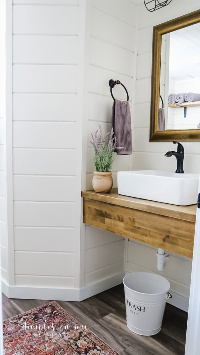 How we created a modern farmhouse bathroom retreat in dingy basement bathroom. Where we splurged and where we saved. #bathroom #bathroomremodel #diybathroomremodel #carsiding #shiplapbathroom #bathroomdecor #bathroomdecorideas #luxuryvinylplank #sherwinwilliamsalabaster #smallvesselsink