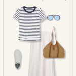 White linen slip skirt, nautical striped tee, sneakers, and a raffia bag pulled from a size-inclusive summer capsule wardrobe create the perfect summer outfit for women over 50.